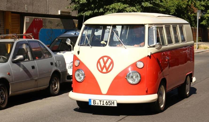 An old VW bus drives on a street in Berlin